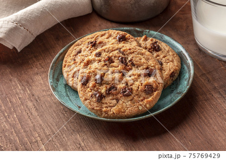 A closeup of chocolate chip cookies with milk on a dark wooden table 75769429