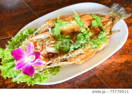 Fried fish with herb and vegetable, cooked food sea bass fish fillet on plate on wooden table Fried fish with herb and vegetable, cooked food sea bass fish fillet on plate on wooden table 75770011
