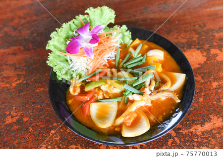 Stir fried squid with salted egg yolk on white dish on table background, curry squid 75770013