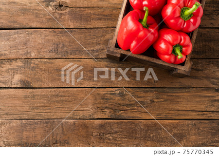 Overhead shot of red sweet paprika in box on old wooden background with copyspace. Bell pepper. Top view Overhead shot of red sweet paprika in box on old wooden background with copyspace. Bell pepper. Top view 75770345