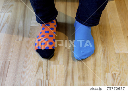 Man wearing different socks standing on the wooden floor. Man wearing different socks standing on the wooden floor. 75770627