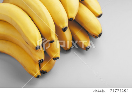 A bunch of fresh yellow bananas on a gray background in the fashionable colors of 2021 A bunch of fresh yellow bananas on a gray background in the fashionable colors of 2021 75772104