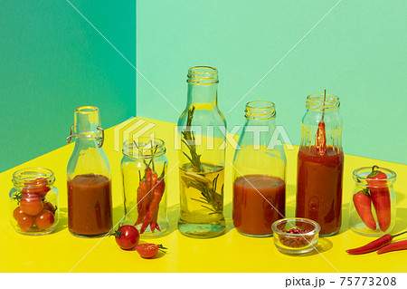 homemade tomato sauce and olive oil in glass bottles on trendy yellow fresh tomatoes and pepper 75773208
