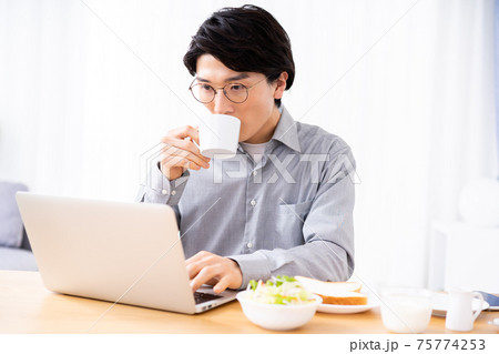 朝食を食べながらノートパソコンを使う若い男性 75774253