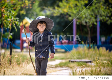 Toddler boy in pointed hat playing with magic wand outdoors. Little wizard. Halloween concept 75774450