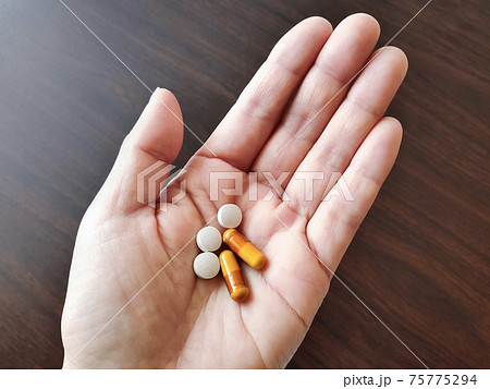 手のひらに乗せたサプリメント 75775294