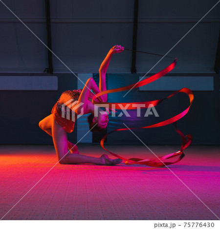 Young graceful girl gymnast isolated over colored background in neon light 75776430