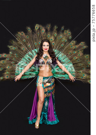 Oriental woman in luxurious peacock feather dress 75776658