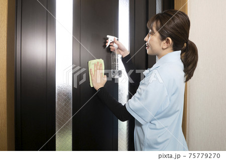 玄関のドアの拭き掃除をするハウスクリーニング の女性 玄関のドアの拭き掃除をするハウスクリーニング の女性 75779270
