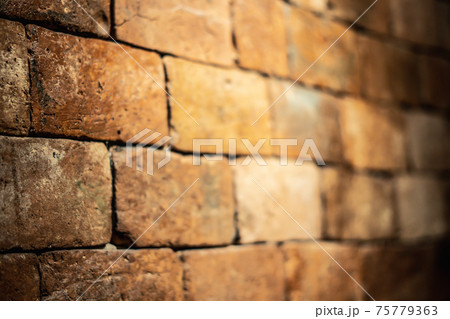 Side view of a backlit red orange shabby brick wall. Blurred focus Side view of a backlit red orange shabby brick wall. Blurred focus 75779363