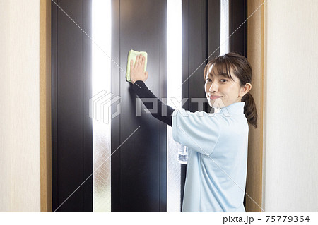 玄関の扉を拭くハウスクリーニング の女性 玄関の扉を拭くハウスクリーニング の女性 75779364