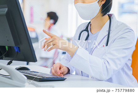 マスクをして仕事をする女性医師 マスクをして仕事をする女性医師 75779880