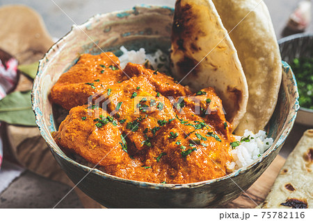 Chicken curry in spicy sauce with rice and chapati bread, dark background, close up. Indian cuisine concept. Chicken curry in spicy sauce with rice and chapati bread, dark background, close up. Indian cuisine concept. 75782116