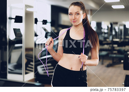Portrait of a fit girl with jumping rope standing in a gym Portrait of a fit girl with jumping rope standing in a gym 75783397