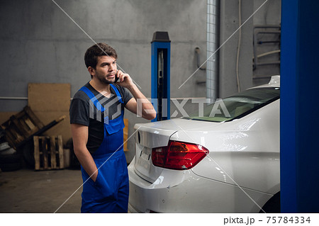 A man is standing by the car and talking on the phone 75784334