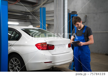 Man with a tablet in his hands inspects the car 75784339