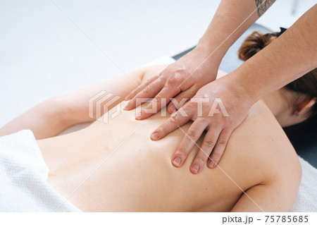 Top close-up view of male masseur massaging back and shoulders of female lying on massage table 75785685