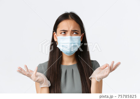 Small business owners, covid-19, preventing virus measures concept. Close-up of annoyed and confused asian woman cant understand something, wear medical mask with gloves and shrugging Small business owners, covid-19, preventing virus measures concept. Close-up of annoyed and confused asian woman cant understand something, wear medical mask with gloves and shrugging 75785825