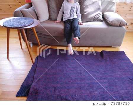 明るい日が差し込むリビングでくつろぐ子ども 顔なし の写真素材