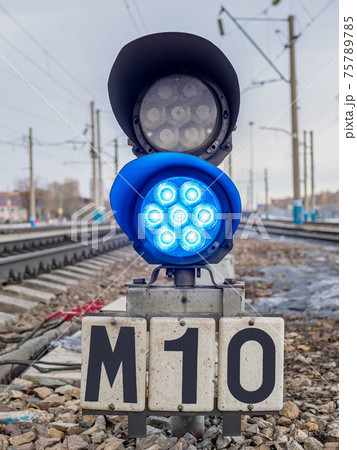 Dwarf railway traffic light with blue-light signal standing near the railway tracks. Dwarf railway traffic light with blue-light signal standing near the railway tracks. 75789785