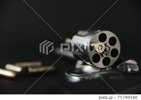 357 magnum caliber revolver pistol, cylinder open with a single bullet protruding from the gun 75790580
