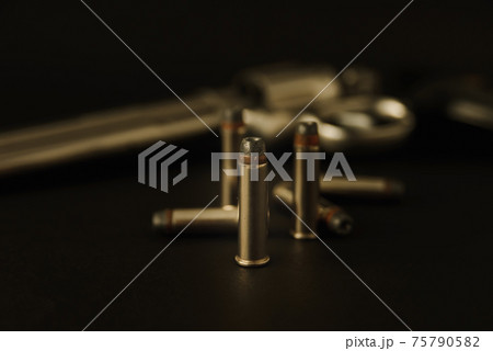 357 Caliber hollow point bullets near revolver pistol gun on black background 75790582