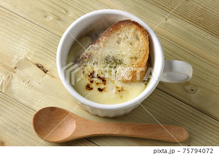 チーズに焦げ目のついてるフランスパンが入った熱々のオニオンスープと木製スプーンを俯瞰で撮影 75794072