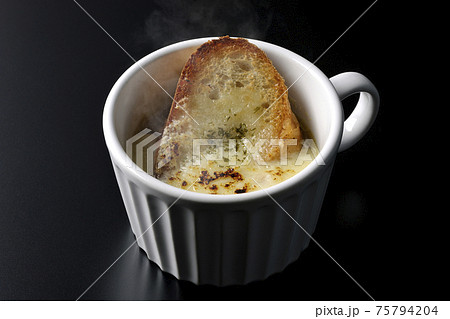 カップで食べる熱々オニオングラタンスープを黒背景で撮影 75794204