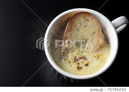 カップで食べる熱々オニオングラタンスープを黒背景で撮影（俯瞰） 75794250