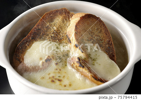 焦げ目のついたチーズ、フランスパンが入ってる熱々のオニオンスープを黒背景で撮影 75794415