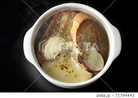 焦げ目のついたチーズ、フランスパンが入ってる熱々オニオンスープを黒背景で撮影（俯瞰） 75794443