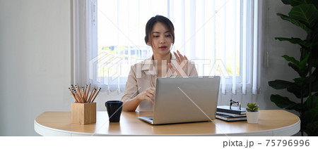 Young businesswoman using laptop computer virtual video conference with her business partner. Young businesswoman using laptop computer virtual video conference with her business partner. 75796996