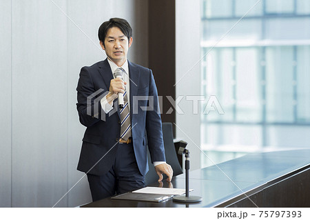 マイクを持って話すビジネスマン 75797393