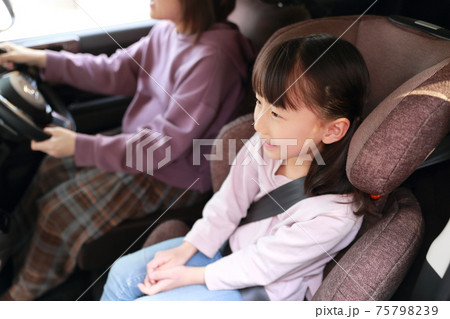助手席に取り付けたジュニアシートに座る女の子の写真素材