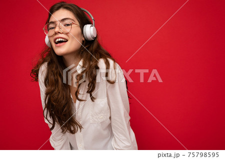 Photo of attractive positive smiling young brunet woman wearing white shirt and optical glasses 75798595