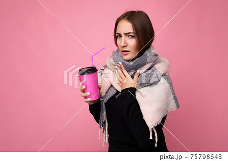 Photo shot of beautiful young brunette woman wearing black sweater and warm scarf isolated over pink Photo shot of beautiful young brunette woman wearing black sweater and warm scarf isolated over pink 75798643