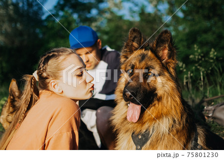 Active Family, fitness couple, Pet Love, Dog Training, best dog breeds for family. Young sports couple walking with two German Shepherd dogs outdoors in summer park Active Family, fitness couple, Pet Love, Dog Training, best dog breeds for family. Young sports couple walking with two German Shepherd dogs outdoors in summer park 75801230