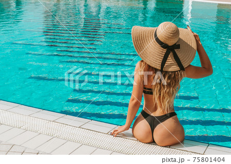 Summer pool relaxing. Young sexy woman in Sun hat, bikini swimsuit, sunglasses swimming in blue water. Trendy summer concept. 75801404