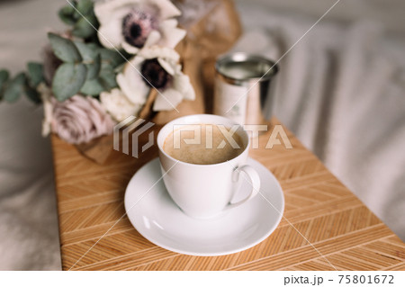 Coffee table on bed. Flowers, coffee cup and candles. Interior gray tones, plaid 75801672