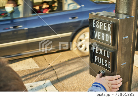 A child presses a button on a traffic light to activate the green phase and be able to safely cross the street A child presses a button on a traffic light to activate the green phase and be able to safely cross the street 75801835