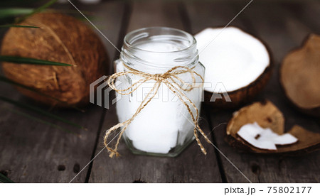 Broken coconuts on gray wooden background with oil jar. White coconut pulp 75802177