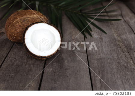 Broken coconuts on gray wooden background with palm leaf. White coconut pulp 75802183