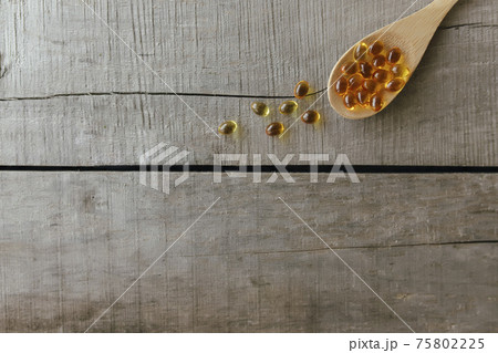 Omega 3 capsules on spoon on wooden background. Health concept. Vitamin pills Omega 3 capsules on spoon on wooden background. Health concept. Vitamin pills 75802225