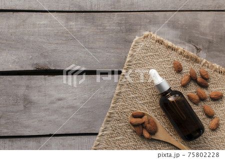 Almond essential oil in glass bottle with spoon. Cosmetic concept 75802228