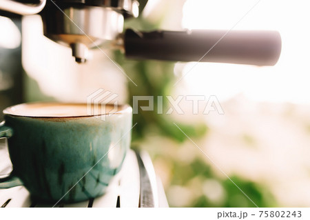 Green cup of coffee at the coffee maker machine, coffee time. Blurred background Green cup of coffee at the coffee maker machine, coffee time. Blurred background 75802243