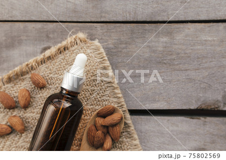 Almond essential oil in glass bottle with spoon. Cosmetic concept 75802569