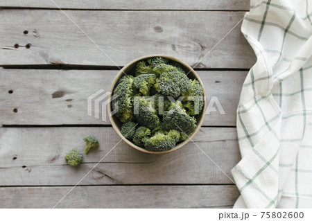 Green fresh broccoli in bowl on wooden background. Healthy eating concept Green fresh broccoli in bowl on wooden background. Healthy eating concept 75802600
