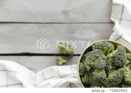 Green fresh broccoli in bowl on wooden background. Healthy eating concept Green fresh broccoli in bowl on wooden background. Healthy eating concept 75802602