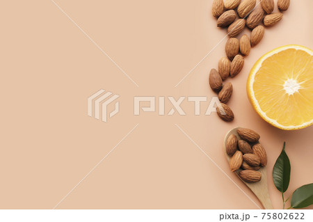 Raw almond kernels in spoon, orange, herbs. Cosmetic, healthy food concept 75802622
