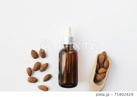 Almond essential oil in glass bottle, spoon, raw almond nuts. Cosmetic concept Almond essential oil in glass bottle, spoon, raw almond nuts. Cosmetic concept 75802626